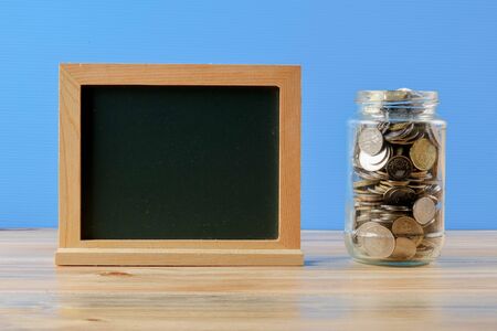 Mason jar with coins over blue back drop. Saving concept.の写真素材