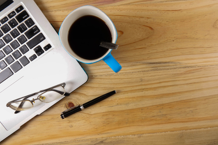 Office wooden desk table with laptop and coffee cup. Top view with copy spaceの写真素材