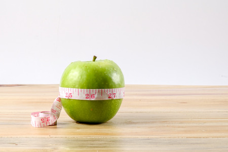 Measuring tape and green apple on wooden background.の写真素材