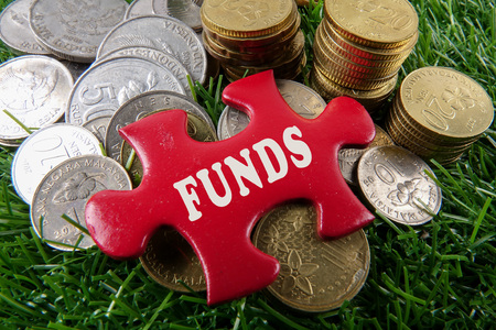 Red colour missing jigsaw puzzle and coins with FUNDS word on the green background.の写真素材