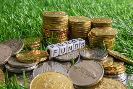Coins and FUNDs word on green background. Business and saving concept.の写真素材