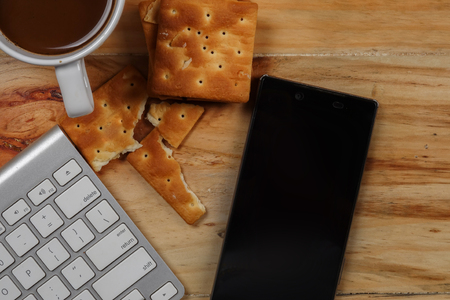 Keyboard,smartphone,pen,biscut,coffee on the wooden table. Top view.の写真素材