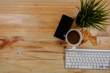 Keyboard,smartphone,notepad,pen,biscut,coffee and green plant on the wooden table. Top view.の写真素材