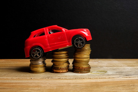 Miniature car on coin stack. Auto trasportation conceptual.