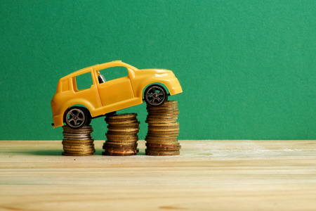 Miniature car on coin stack. Auto trasportation conceptual.