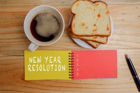 NEW YEAR RESOLUTION: Blank notepad and coffee cup on office wooden tableの写真素材