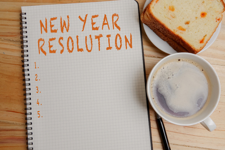 NEW YEAR RESOLUTION: Blank notepad and coffee cup on office wooden tableの写真素材
