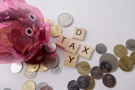 TAX DAY CONCEPT: Wooden letter of TAX DAY arranged with coins on white background.の写真素材