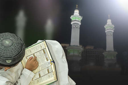 Boy reading holy book, Quran with blur background of Mecca.の写真素材
