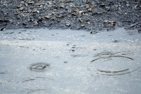 Rain on asphalt or tarmac road creating ripples, Blurred,high contrast and selective focus image.の写真素材