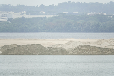 Dredging panning sand on the beach during the construction of a new sea freight terminal in the harbor of port.の写真素材