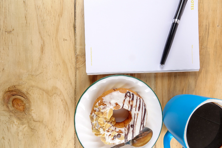 Business concept - Top view donut,notebook , pen, coffee cup, and phone on wood table.の写真素材