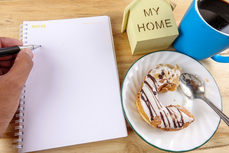 Business concept - Top view donut,notebook , pen, coffee cup, and phone on wood table.の写真素材