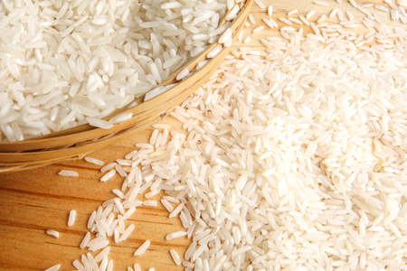 Fresh rice in wicker basket over a wooden table. Side lighting effect.の写真素材