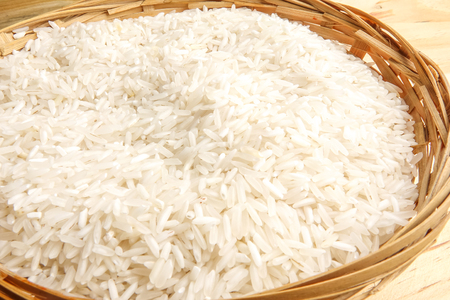 Fresh rice in wicker basket over a wooden table. Side lighting effect.の写真素材