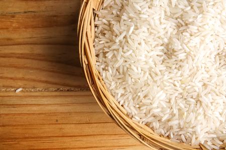 Fresh rice in wicker basket over a wooden table. Side lighting effect.の写真素材