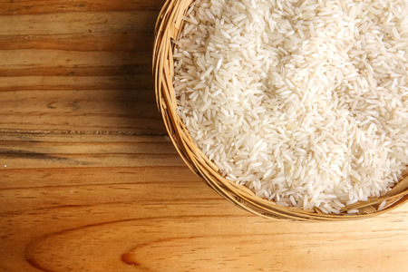 Fresh rice in wicker basket over a wooden table. Side lighting effect.の写真素材