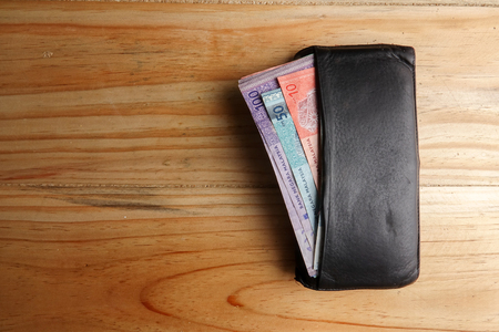 Leather men's open wallet with Malaysia banknotes and credit card inside  on a wooden background.の写真素材