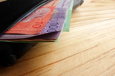 Leather men's open wallet with Malaysia banknotes and credit card inside  on a wooden background.
