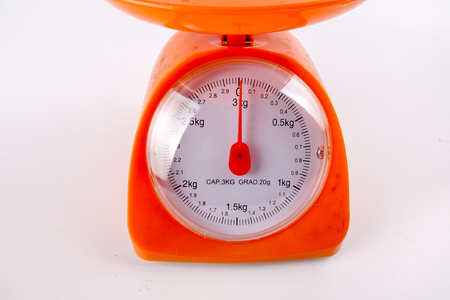 A Orange colour weight measurement balance isolated white backgroundの写真素材