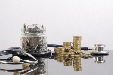 Medical cost concept with stethoscope and coins on white background.の写真素材