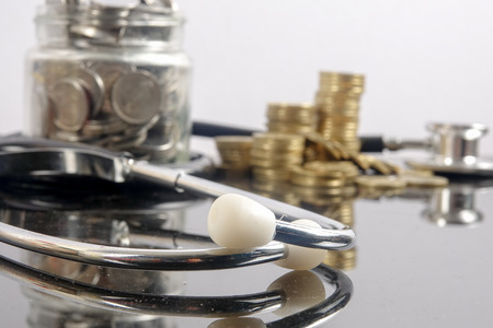 Medical cost concept with stethoscope and coins on white background.の写真素材