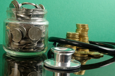 Medical cost concept with stethoscope and coins .on a green background.の写真素材