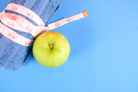 Fitness concept with dumbbell,hand gripper,tower and measuring tape on a blue background.の写真素材