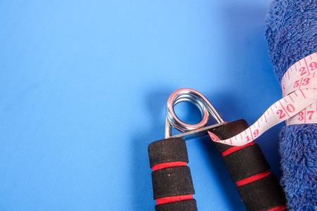 Fitness concept with dumbbell,hand gripper,tower and measuring tape on a blue background.の写真素材