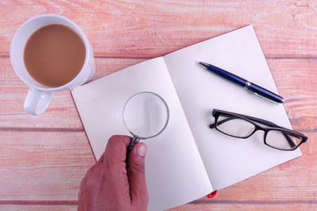 Top view of wooden office table with coffee,notes,coffee and glasses.の写真素材