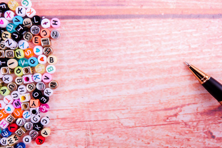 Colorful plastic alphabet dice on a wooden background as a background.
