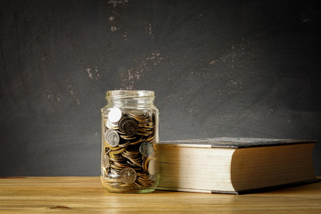 EDUCATION FUND CONCEPT with coins in a glass jar and old book.の写真素材
