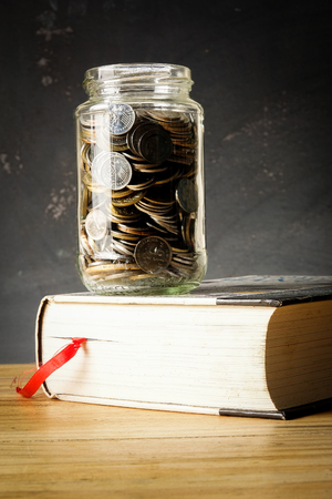 EDUCATION FUND CONCEPT with coins in a glass jar and old book.の写真素材
