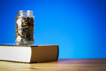 EDUCATION FUND CONCEPT with coins in a glass jar and old book.の写真素材