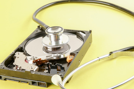 RECOVERY AND REPAIR TECHNOLOGY CONCEPT: Hard Disk Drive (HDD) with stethoscope isolated on a yellow...