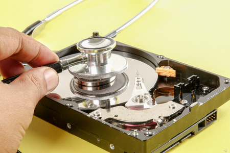 RECOVERY AND REPAIR TECHNOLOGY CONCEPT: Hard Disk Drive (HDD) with stethoscope isolated on a yellow backgroundの写真素材