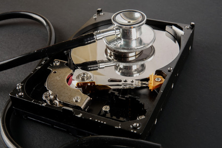 RECOVERY AND REPAIR TECHNOLOGY CONCEPT: Hard Disk Drive (HDD) with stethoscope isolated on a black backgroundの写真素材