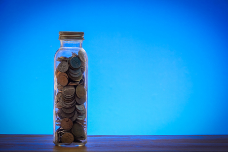 Saving concept with mason jar,coins and piggy bank on a blue background.の写真素材