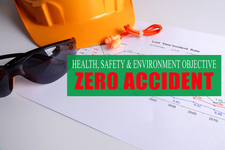HEALTH,SAFETY & ENVIRONMENT OBJECTIVE: ZERO ACCIDENT with yellow hardhat ,safety glass and ear plug over accident statistic graph.の写真素材