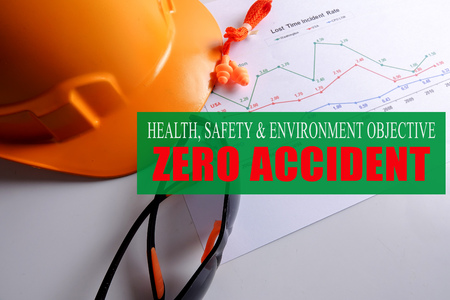 HEALTH,SAFETY & ENVIRONMENT OBJECTIVE: ZERO ACCIDENT with yellow hardhat ,safety glass and ear plug over accident statistic graph.の写真素材