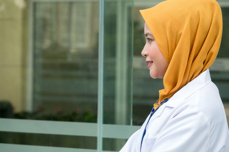 Confident female doctor standing infront of  office and smiling at camera, health care and prevention conceptの写真素材