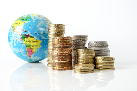 Global economy concept with sphere globe and stacked of coins over white.の写真素材