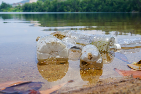 Bad enviromental habit of improper disposal of non-biodegradable PVC cups and bottles in a lake. Selective focusの写真素材