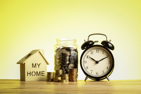 Housing saving concept with stacked coins,house model and alarm clock.の写真素材
