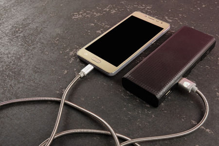 Smartphone and powerbank on rustic black background.の写真素材