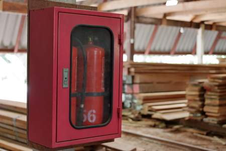 Fire extinguishers on blurry stack of wood in warehouse