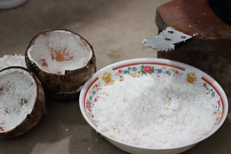 Close up blade of coconut grater with coconut grated in bowl , Shallow depth of field , light and shadowの写真素材