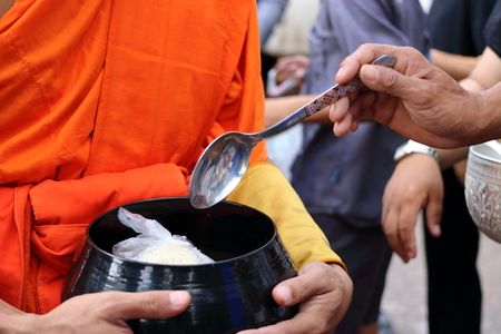 Hands of people while put food to a Buddhist monk's alms bowl in  the end of Buddhist Lent Dayの写真素材