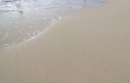 Wave and foam on the sand beach backgroundの写真素材