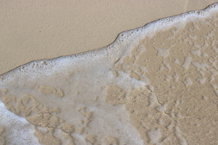 Wave and foam on the sand beach backgroundの写真素材